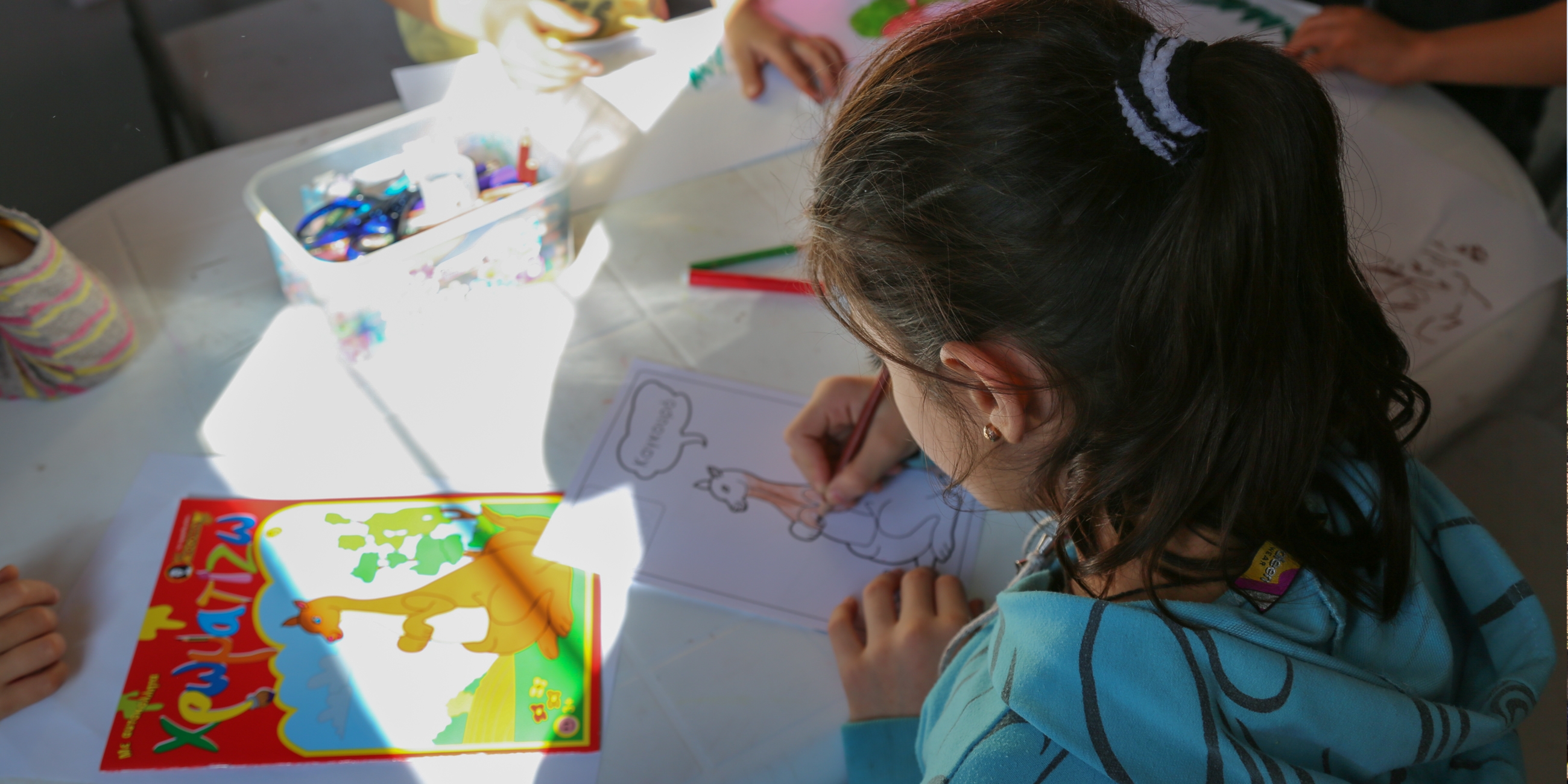 Rula*, 7, draws pictures at Save the Children’s child-friendly space in Kara Tepe. She and her family fled from Syria to Turkey, from where they got on a rubber boat to Lesvos island, Greece. Photo credit: Simine Alam/Save the Children 2015. 