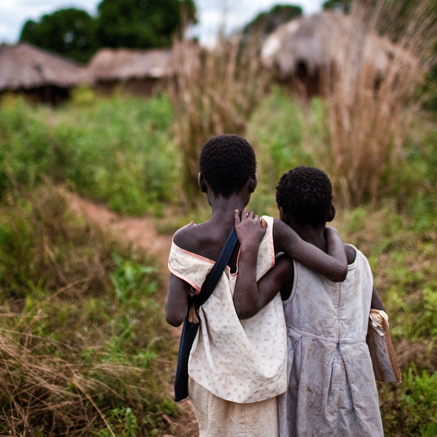 Two young sisters who lost their mother to HIV and AIDS walk home arm-in-arm after school. Photo credit: Save the Children, 2010. 