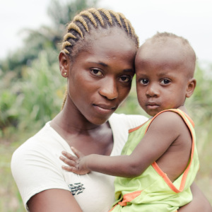A mother holds her young African child, who suffered with pneumonia but was helped to recover, near a road in the Democratic republic of Congo.