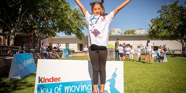 A little girl jumps in the air at a Ferrero Kinder Joy of Moving event.