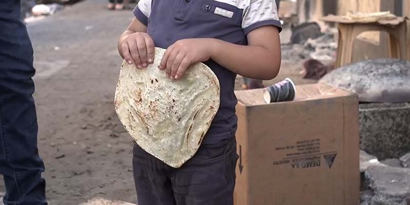 A young boy holds some bread on a street in North Gaza.