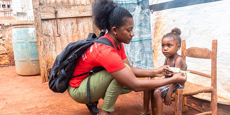Haiti, a Save the Children worker examines the malnutrition of a small child.