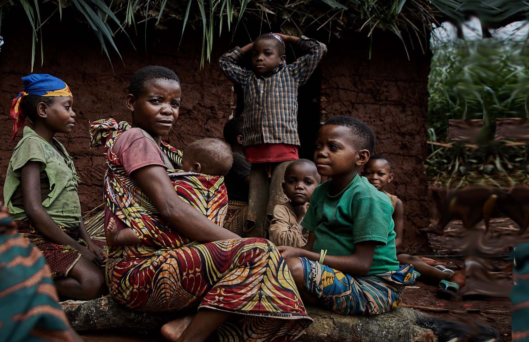 DRC, a family sits together outside their home