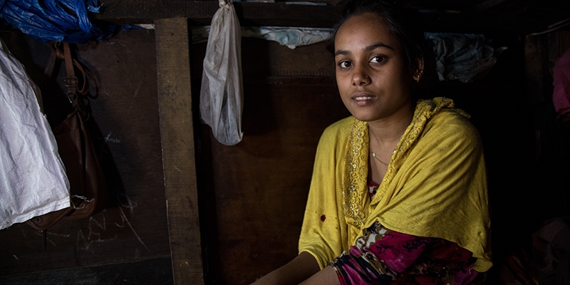 India, a Save the Children child champion, inside her home haphazardly patched together with wood panels 