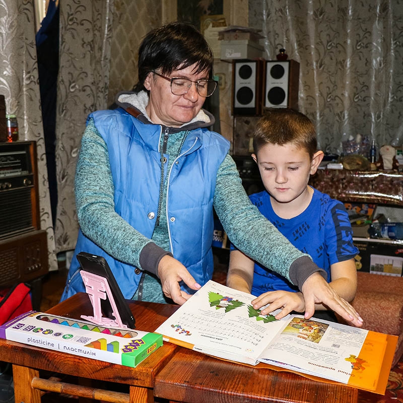 Ukraine, a young boy and his mother join classes together so she can help her son with tasks.
