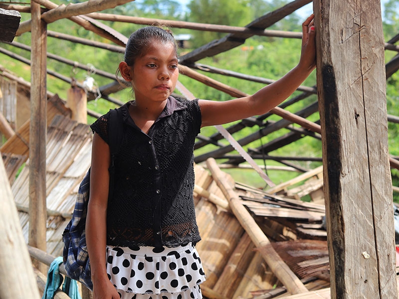 A young girl stands in front of her home that was destroyed in a hurricane in Nicaragua