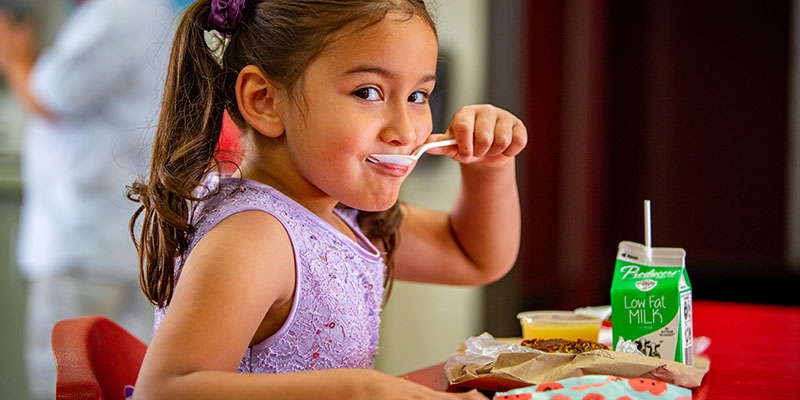 In the U.S., a pre-schooler eats breakfast provided by her school.