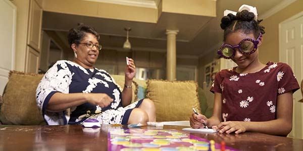A woman and a young girl play a board game together.