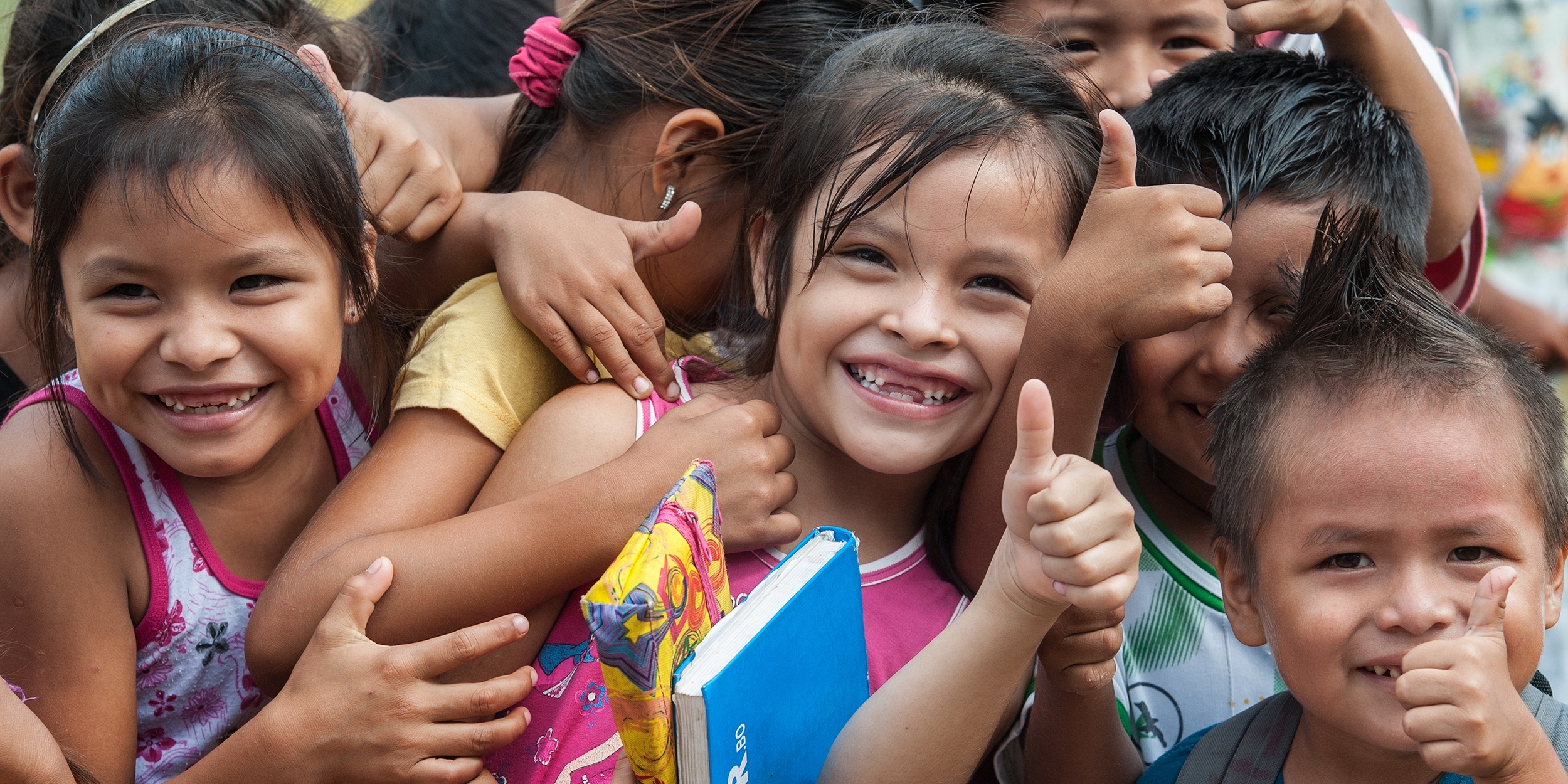 A group of smiling Bolivian children give a big “thumbs up” at an Early Childhood Development program in the village of San Ignacio de Mojos, Bolivia. There are 57 students in the school. Photo credit: Susan Warner/Save the Children, March 2016.