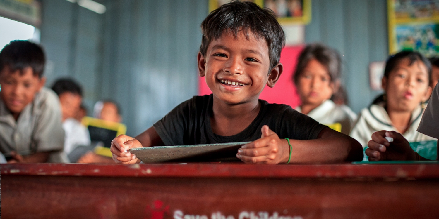 A 6-year-old boy smiles brightly from his classroom in Cambodia. There, Save the Children works with the Provincial Education office to strengthen access to schools and improve the quality of education, giving technical support, and providing materials and furniture to schools. Photo Credit: KJ Borja/Save the Children, March 2013.