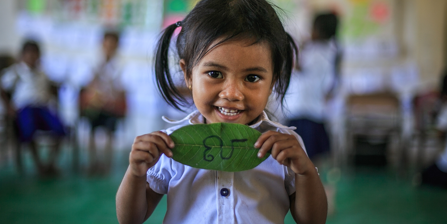 3 year old preschool student Ron Ranty holding up a khmer alphabet during a game that boosts literacy. Photo Credit: Kj Borja/Save the Children 2015