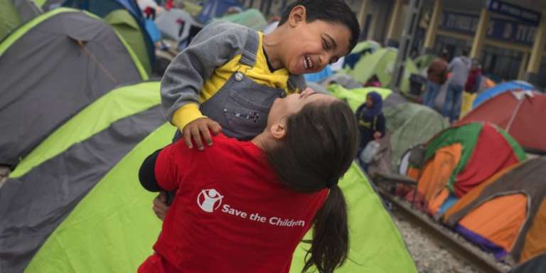  A young child refugee from Syria laughs and plays with Save the Children's Mariluz Garcia in Idomeni at the border between Greece and the Former Yugoslav Republic of Macedonia. More than 10,000 refugees are stranded in Idomeni waiting for the border to open. Save the Children works in Idomeni offering protection to children traveling alone and provides food and support to families. Photo credit: Pedro Armestre, September 2015.