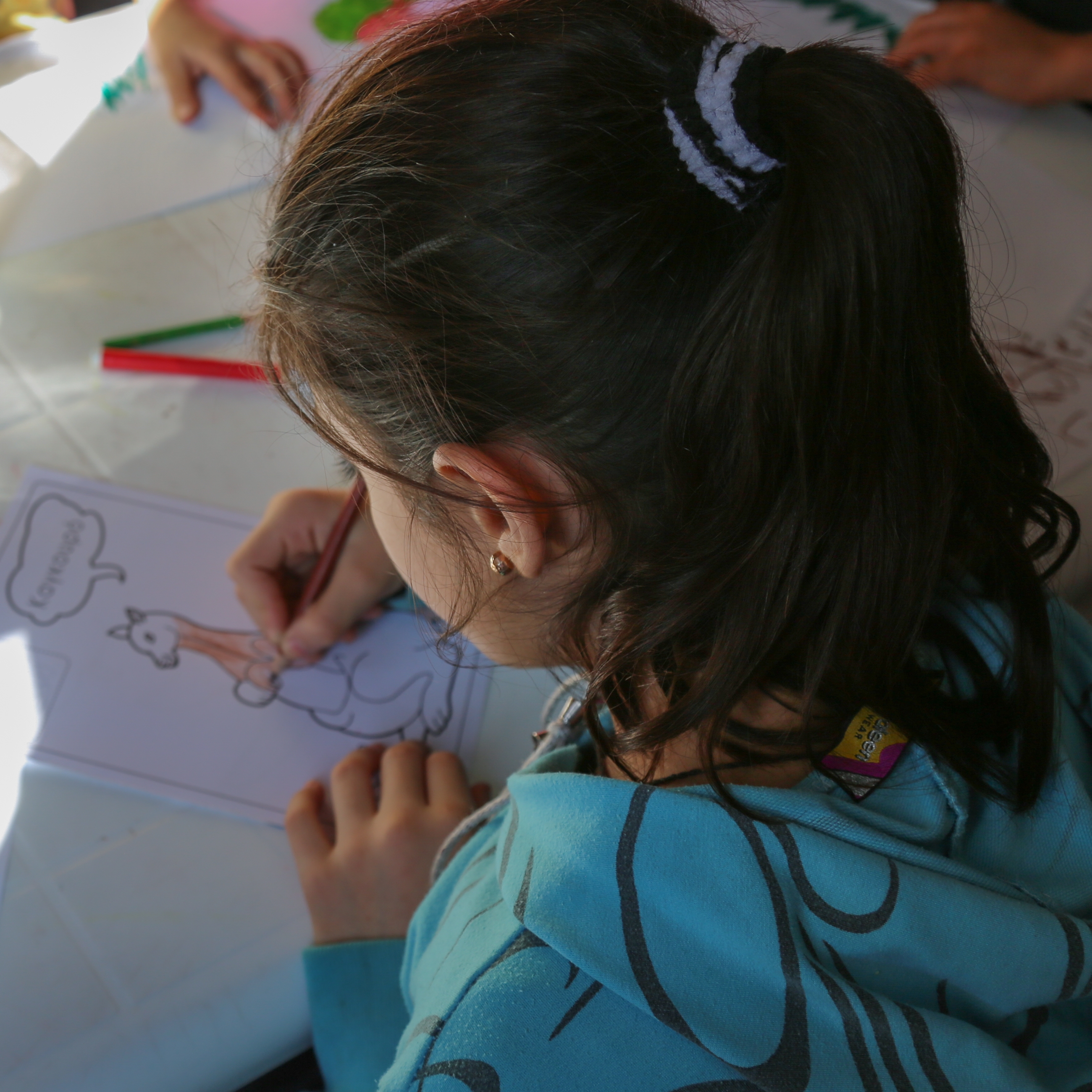 Rula*, 7, draws pictures at Save the Children’s child-friendly space in Kara Tepe. She and her family fled from Syria to Turkey, from where they got on a rubber boat to Lesvos island, Greece. Photo credit: Simine Alam/Save the Children 2015. 
