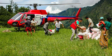 Aid workers carrying supplies from a helicopter. 