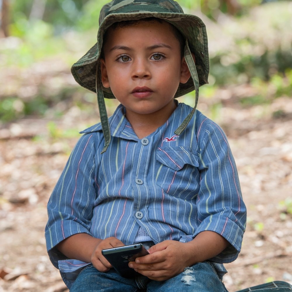 Young Christopher plays with a borrowed cell phone. He lives in Nicaragua, where his parents participate in a livelihoods program through Save the Children. They started producing vegetable seedlings and eventually turned profits and purchased more land. They also improved their family’s nutrition because they received support to grow corn and beans. Photo credit: Susan Warner/Save the Children, August 2016.