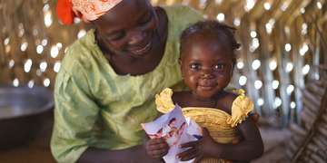 Home at last, this 14-month-old girl and her mother Maria look at photos of herself from her time at a hospital in Dourgou, Niger. Photo credit: Talitha Brauer/Save the Children 2016.