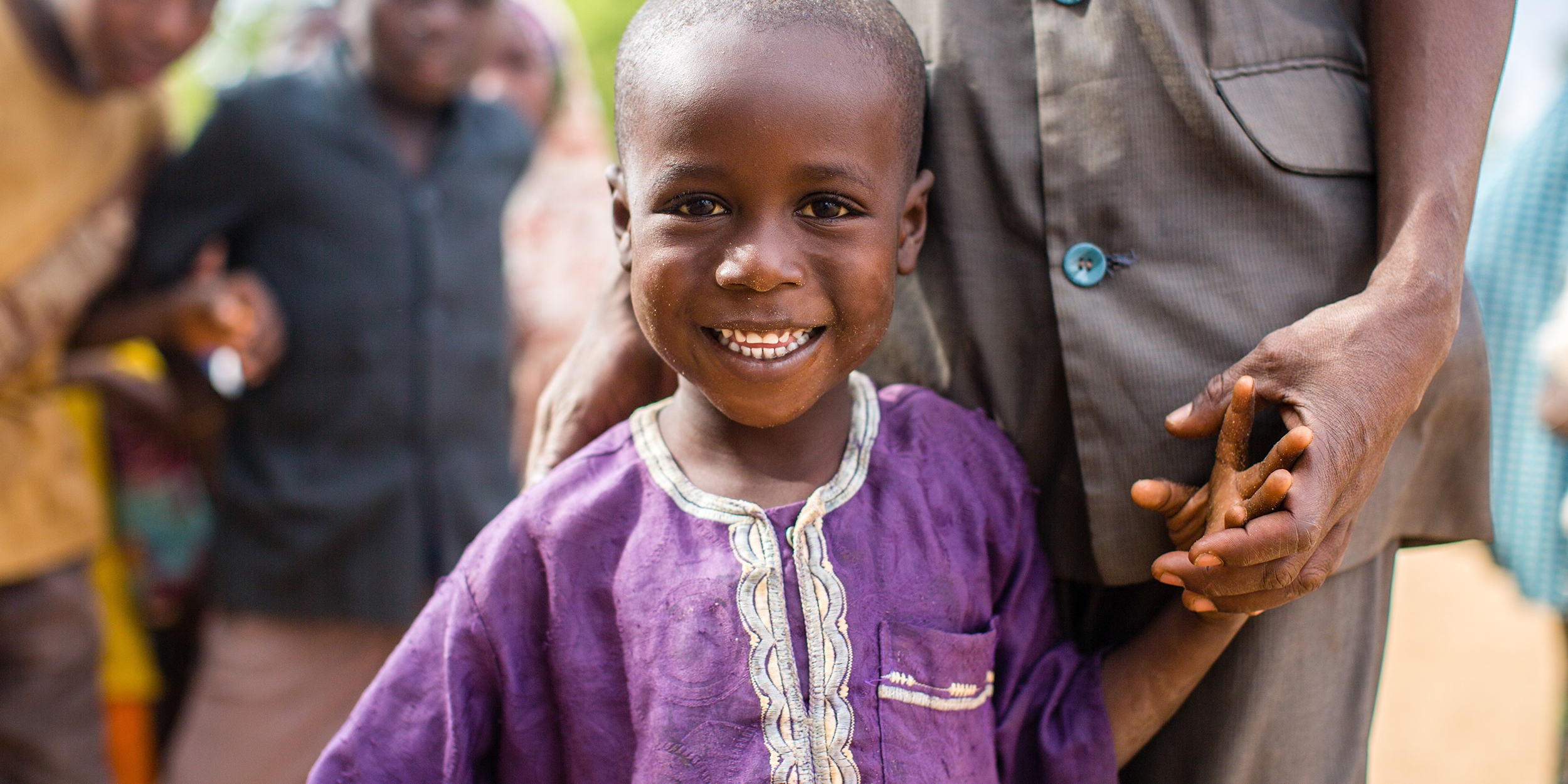 A 6-year-old boy dressed in a bright purple tunic smiles for the camera after an Early Childhood Care and Development class in his community in Maradi, Niger. Photo credit: Victoria Zegler/Save the Children, December 2016. 