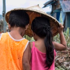 A boy of four and a girl of three walk through their village in Dolores, Eastern Samar, Philippines, after Typhoon Hagupit tore through the region, leaving many with destroyed homes and without bare essentials. Photo Credit: Jonathan Hyams/Save the Children 2014.