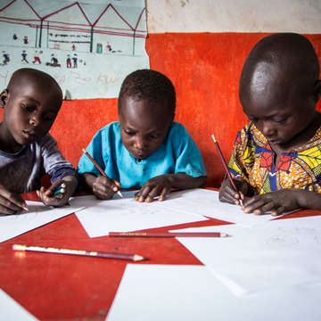 Three boys concentrate on their drawings at an Early Childhood Care and Development (ECCD) center in Burera, Rwanda. Their drawings depict a story from a book provided through Save the Children's support. These structured sessions of being read to – and drawing their interpretations of the story – are part of early literacy activities featured in Save the Children's Signature Education Program. Photo credit: Colin Crowley / Save the Children, March 2014. 