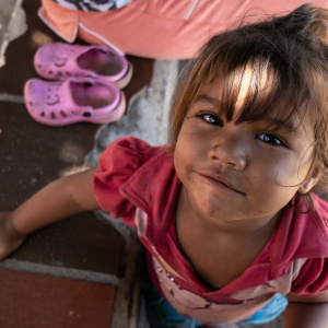 A young girl smiles while standing next to a pair of purple shoes near the Colombia / Venezuela border.
