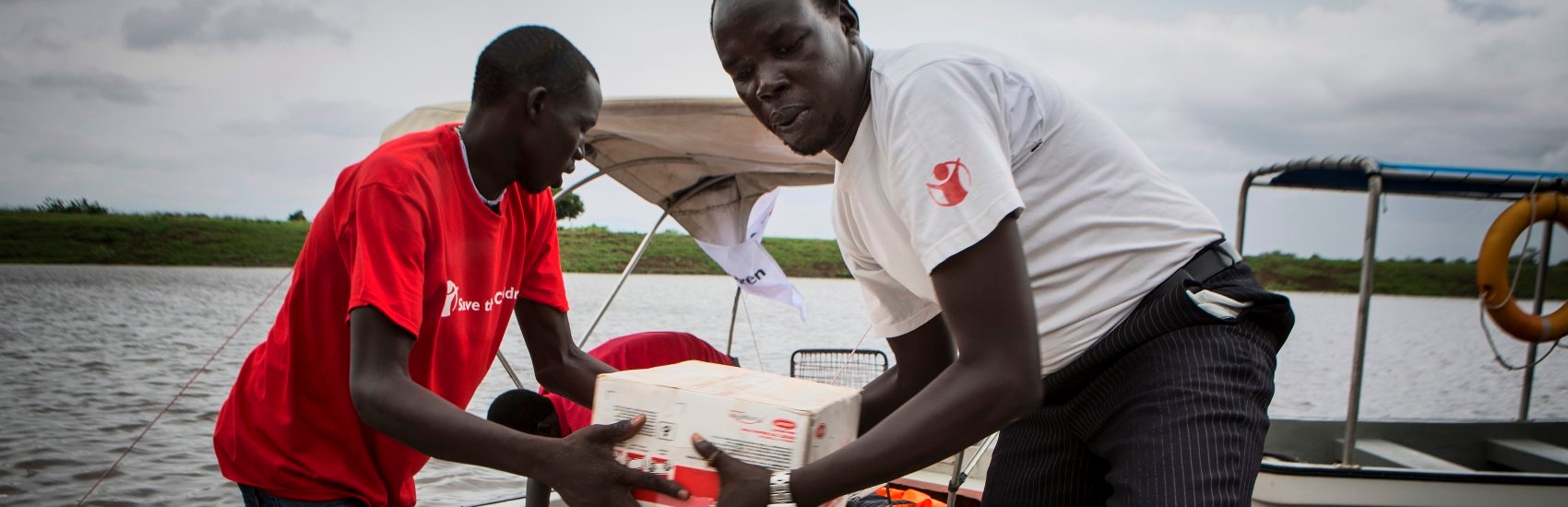 Save the Children field staff offloading a boat with food supplements for malnourished children in remote villages in Akobo, South Sudan. Photo Credit: Jonathan Hyams/Save the Children 2014.