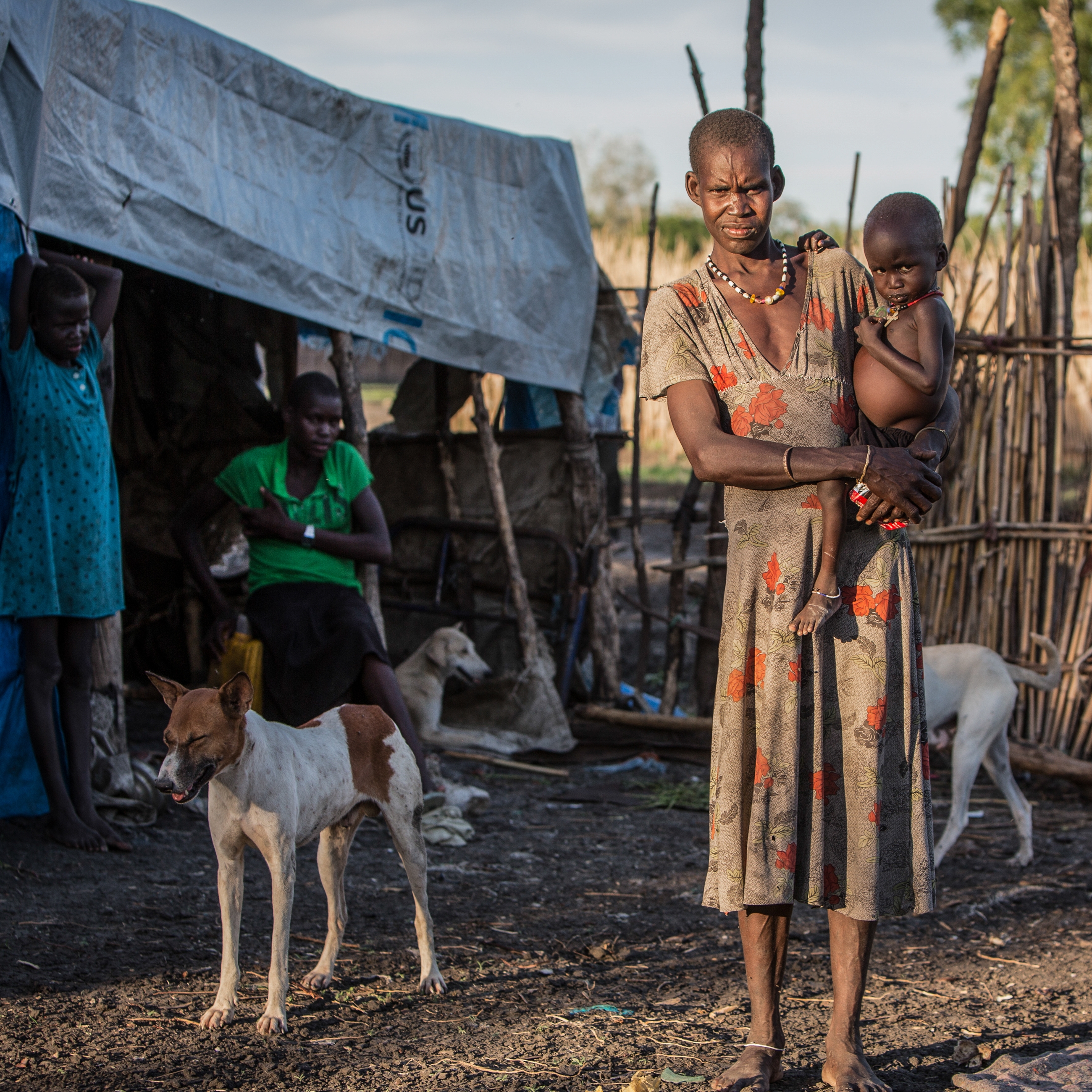 Tahani*, a widow, holding her 3-year-old son Chuol*. Her two daughters – ages 9 and 12 – stand behind her at their temporary home in Akobo, South Sudan. Photo credit: Jonathan Hyams/Save the Children 2015.