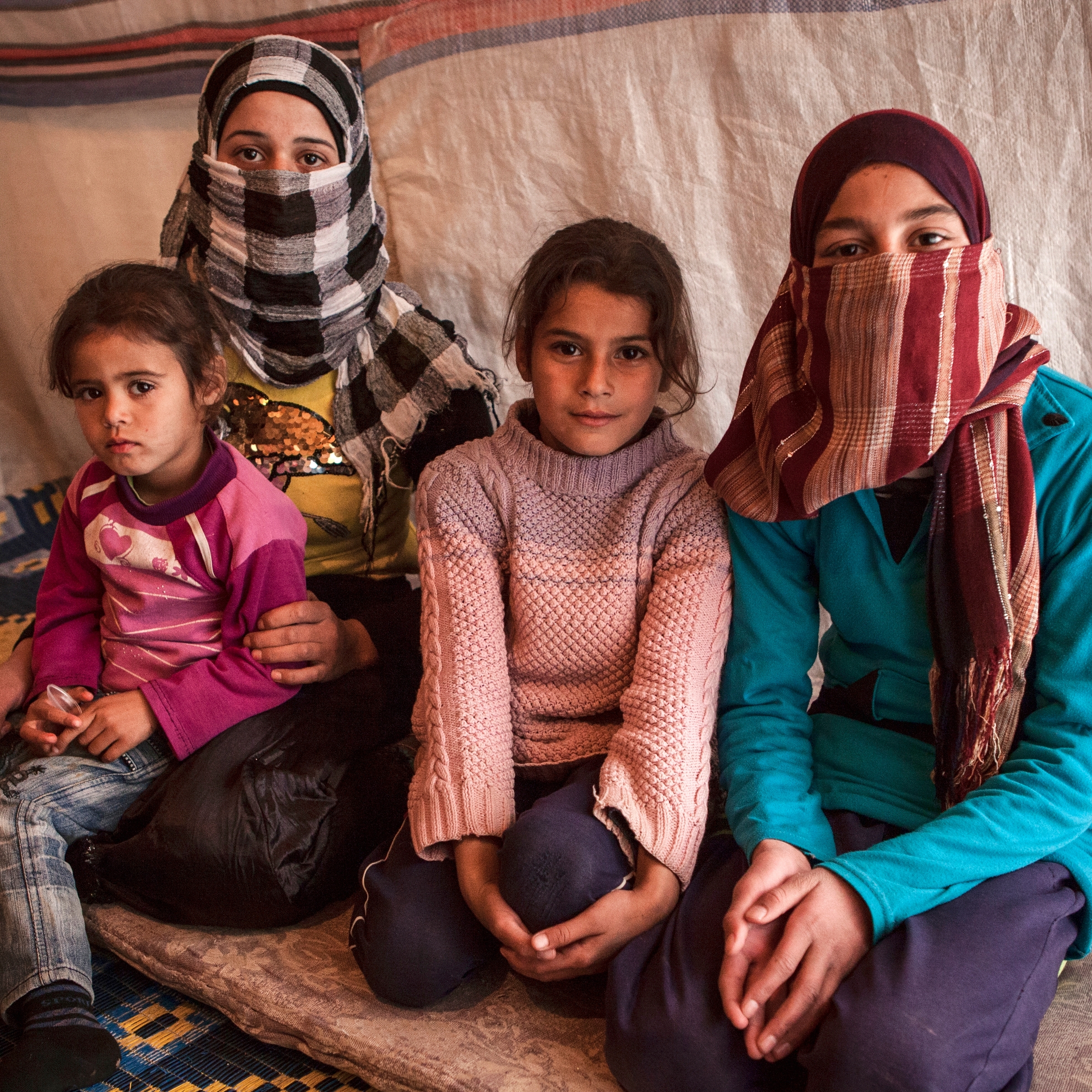 Sana* and her sisters at a refugee settlement near the Syrian border. Save the Children is helping children recover from their experiences within Syria and across the region, to make sure they can access education and to ensure that families have the basic necessities they need to survive – including healthcare, warm clothes, nutritious food and winter shelter materials. Photo Credit: Save the Children 2013.