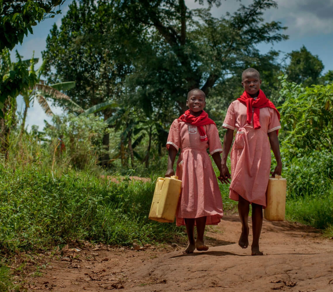 A girl and her friend holding water containers in Uganda.