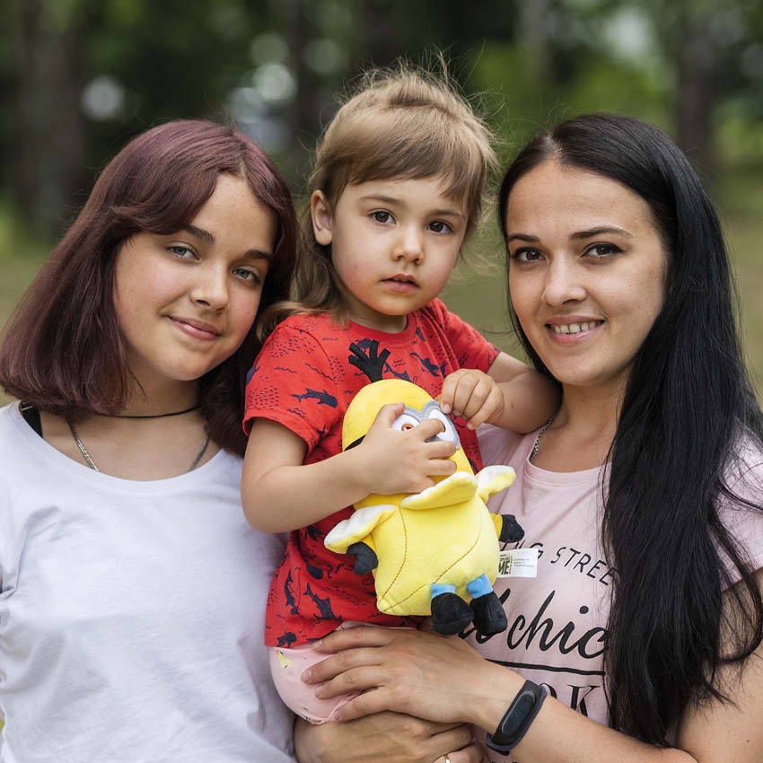 Ukraine, a mother stands with her two girls as they smile at the camera