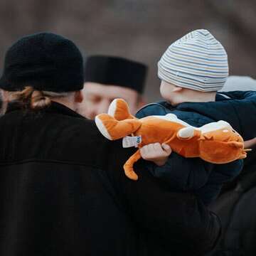 Child being carried to safety holding a stuffed animal.