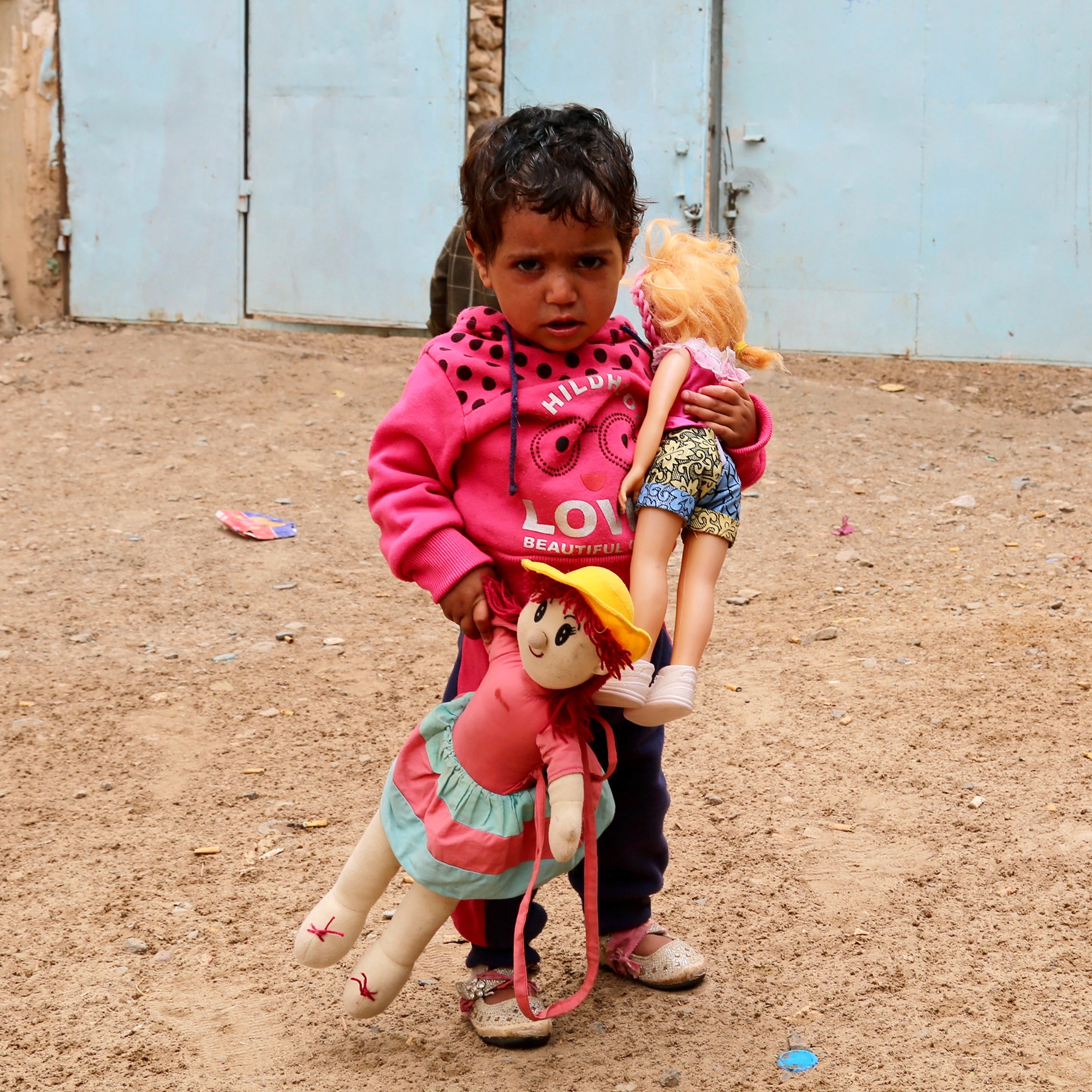 Girl stands with dolls.