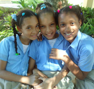 Three girls who are sponsored by Save the Children pose for a photograph in the Dominican Republic