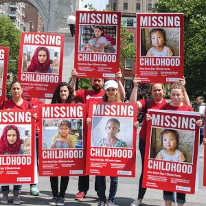 A large group of Save the Children employees hold signs in Washington Square Park that show children’s faces and read, “Missing Childhood.” On International Children’s Day, staff went to various public places with signs detailing the various ways in which children are missing out on their childhood. Photo credit: Ellery Lamm, June 2018.
