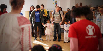 Ashley Snow, a manager of engagement and resource development for Save the Children dances with Roma children and a group of IKEA Foundation employees.