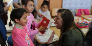Ashley Snow, a manager of engagement and resource development for Save the Children talks to a young Roma girl in at a school in Romainia.