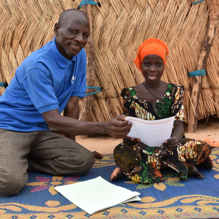 Hamissou reading a letter to Harira, a sponsored child in Niger. Photo credit: Save the Children 2019.