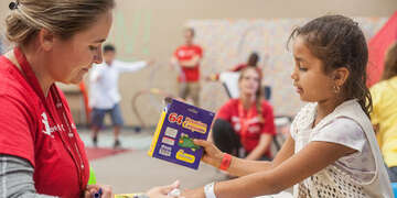 Save the Children's Child protection officer, Jennifer Gulbrandson colors with six-year-old *Sofia in the Save the Children's Child-Friendly Space located at Kazen Middle School in San Antonio, Texas, August 28th, 2017 where hundreds of displaced families, including many with infants and toddlers, are seeking refuge in the wake of Hurricane Harvey. Save the Children’s emergency response team is on the ground in San Antonio, TX, working to meet children and families’ immediate needs as Hurricane Harvey blasts inland from the Texas coastline. The aid organization is delivering emergency supplies, including blankets, portable cribs and strollers, to families forced to evacuate.Photo Credit: Susan Warner for Save the Children*Name changed for child protection purposes. Photo credit: Susan Warner/Save the Children 2017.