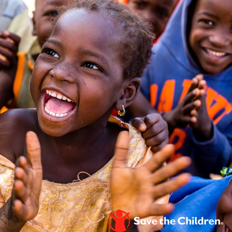 A young sponsored child claps with joy. Photo credit: Save the Children 2018.