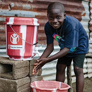 A boy washes his hands using a clean water kit. 