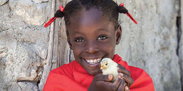 A child holds a baby chick up to the camera