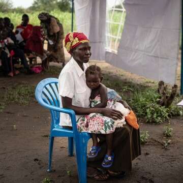 A woman sits with her daughter at a malaria clinic. 