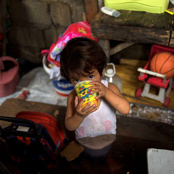 Two-year old Jasmine* from the Philippines drinks a cup of water at her home. Photo credit: Save the Children 2019. 
