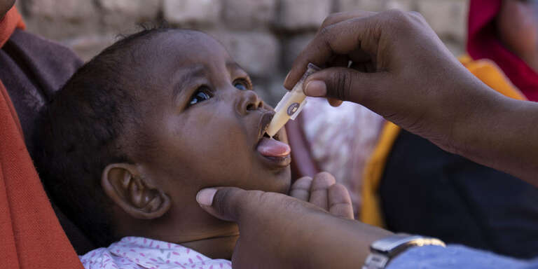 In Sudan, a young child receives a vaccine from a health worker. 
