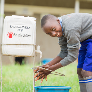 A young boy student utilizing a handwashing facility provided by Save the Children to his school.