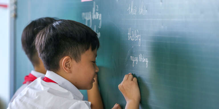 Children in Vietnam write on a chalkboard. 