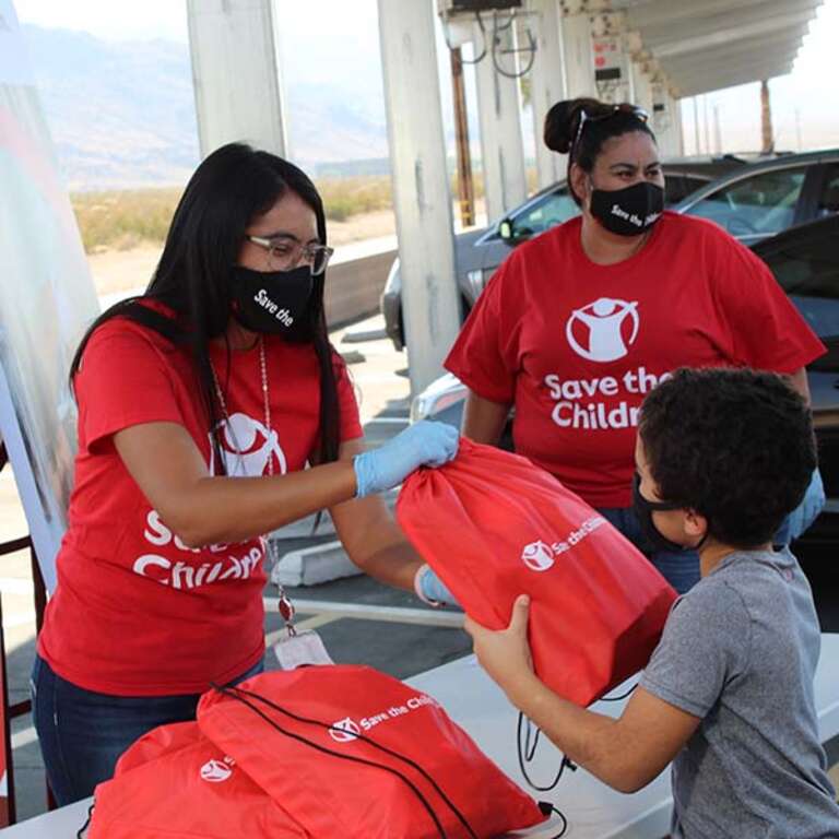 A Save the Children volunteer hands out supplies. 