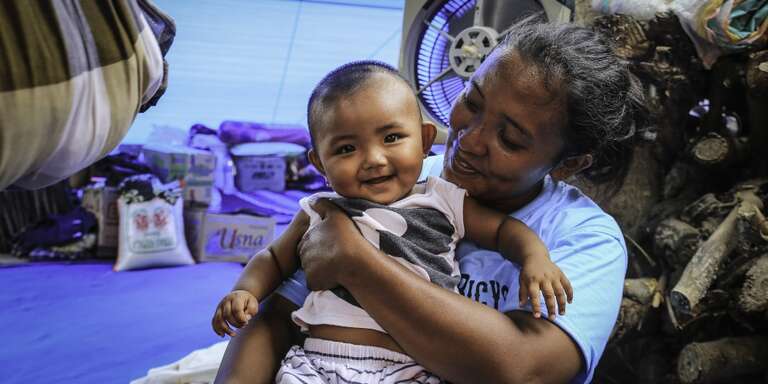 Mother and baby smile despite living in an evacuation camp because of the the earthquake in Indonesia in 2018.