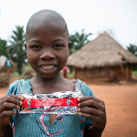 In the Democratic Republic of Congo, an older sister holds up a package of Plumpy Nut