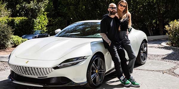 Adam Levine and Behati Pinsloo stand in front of a white Ferrari. 