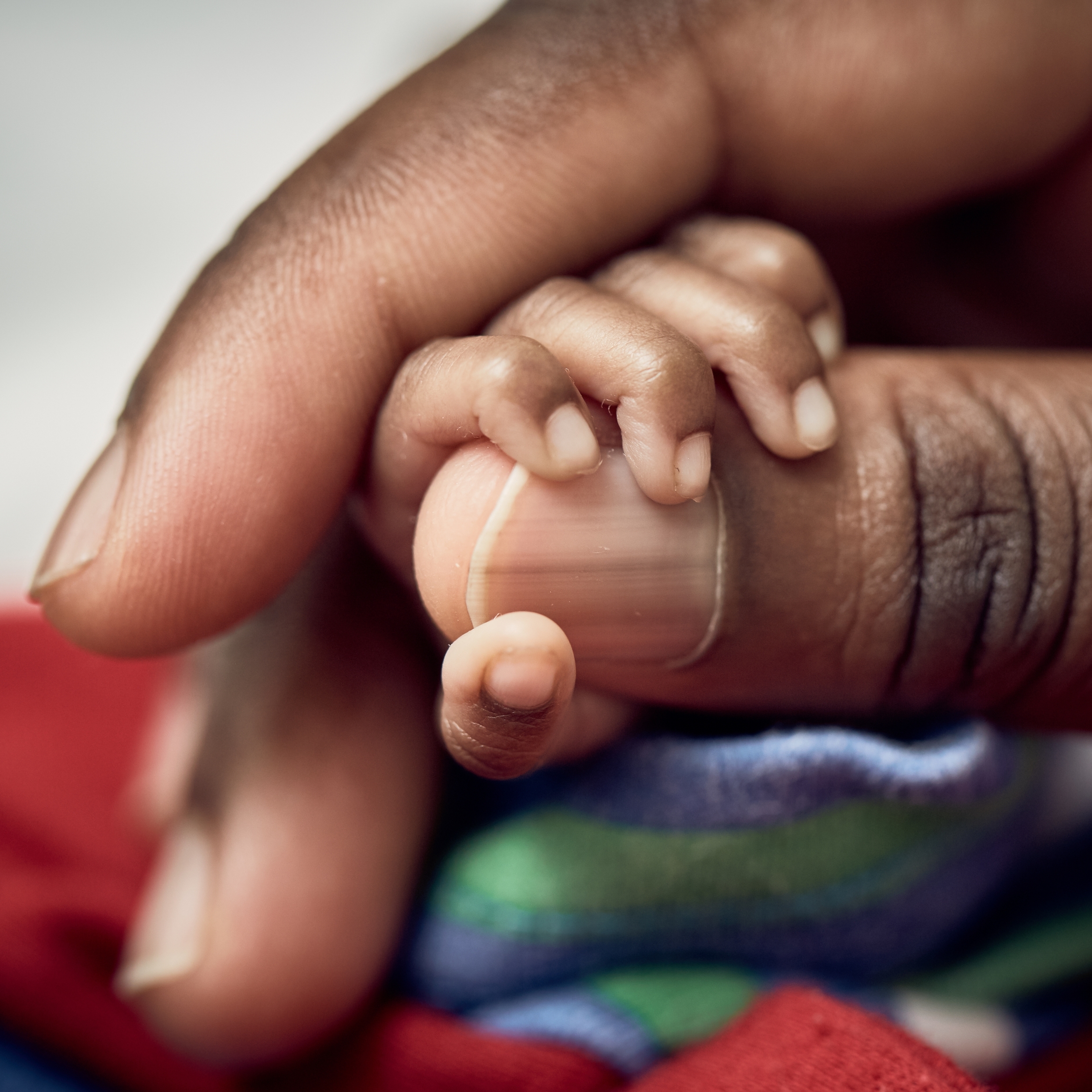 A Ugandan baby’s tiny hand is wrapped around his mother’s thumb.  The baby was born a twin and born prematurely – at 7 months – with a birthweight of 1.13 and .95kgs each. The mother is being taught Kangaroo Mother Care, a lifesaving technique that encourages skin-to-skin contact and breastfeeding for premature babies. Photo credit: Juozas Cernius/Save the Children, March 2018.